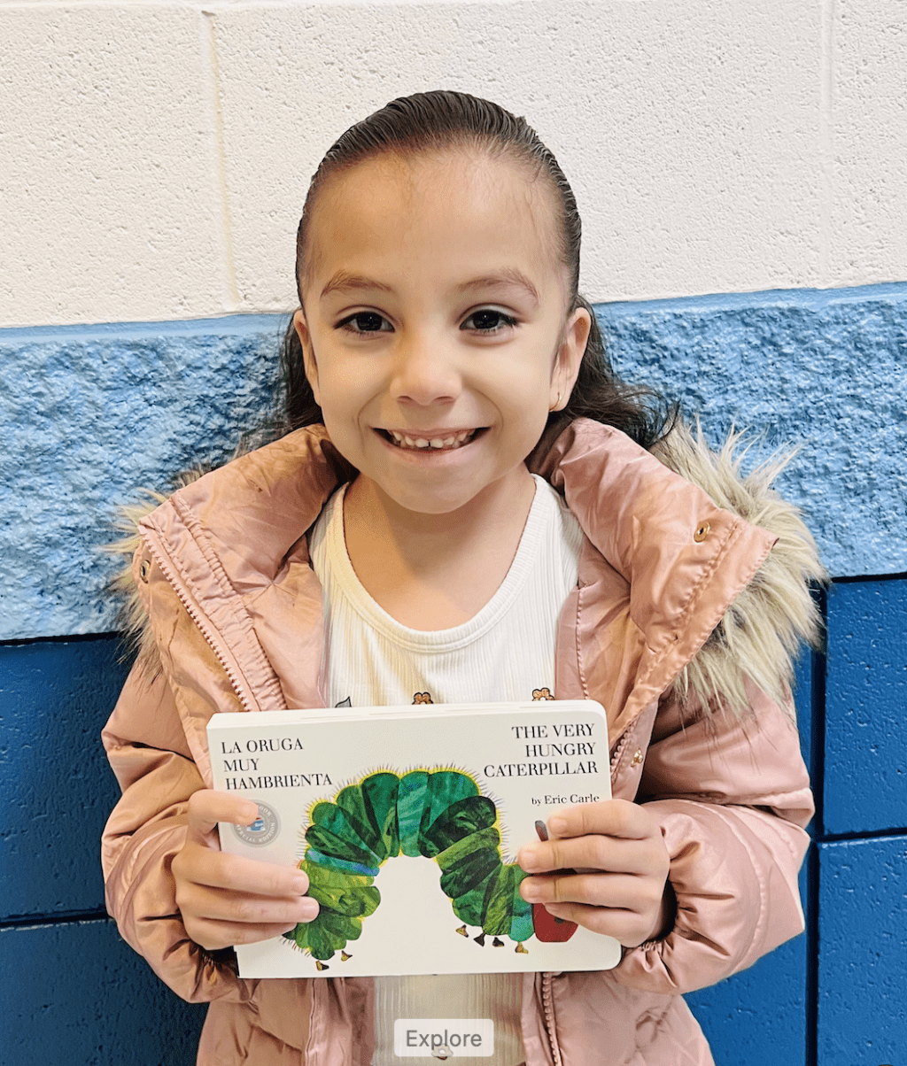 student holding a book received for earning a  praise award